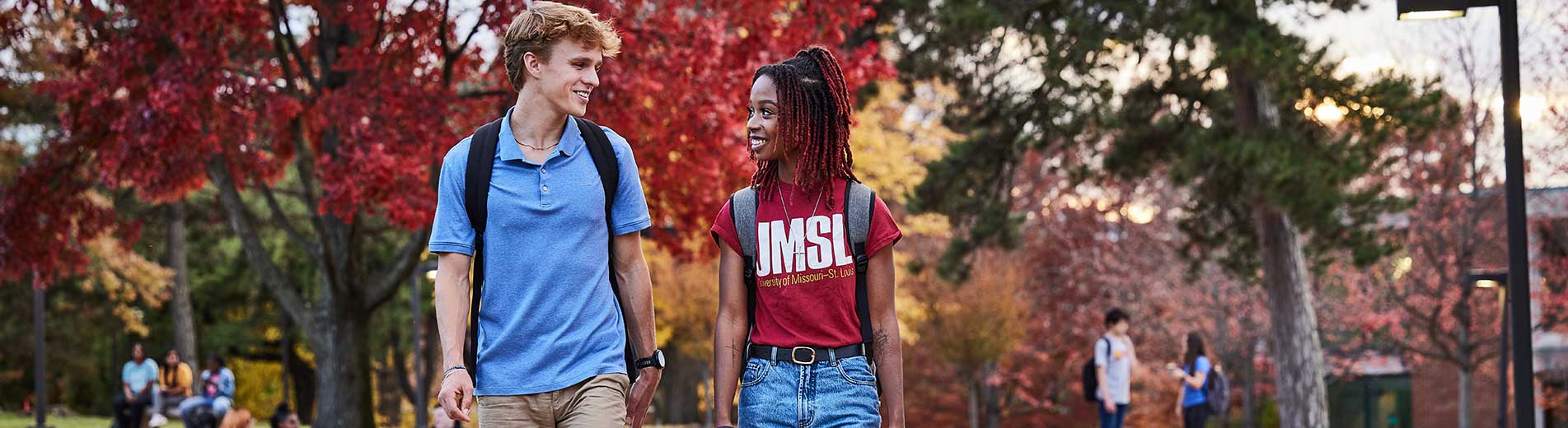 two students walking on campus smiling at each other