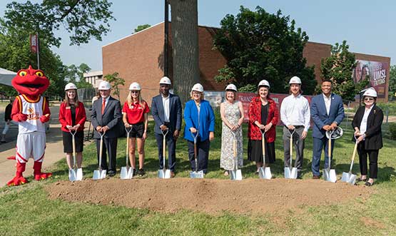 faculty and staff and a mascot with shovels