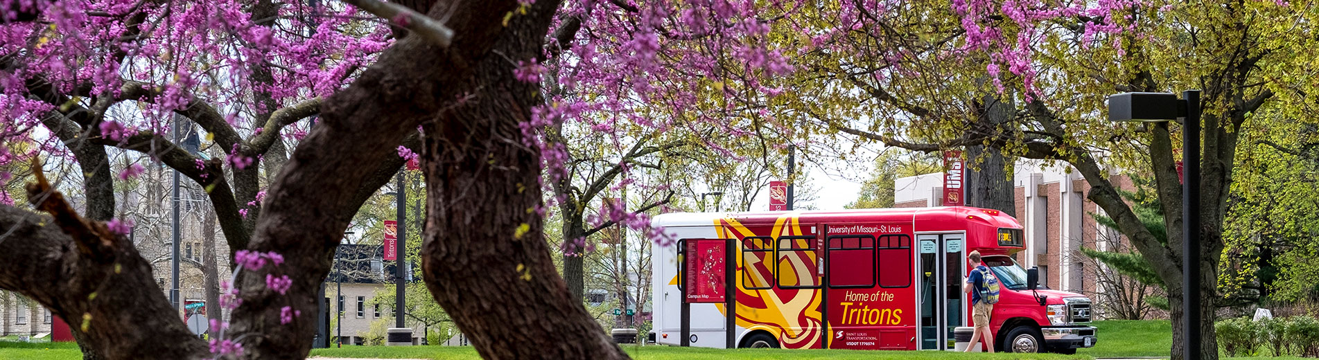 shuttle bus on campus with spring blooming trees