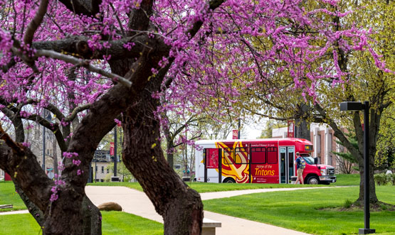 shuttle bus on campus with spring blooming trees