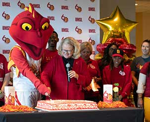 cutting a cake with a mascott